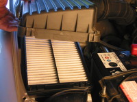 To check and replace a car air filter, remove the cover held on by screws or clips.