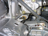 To remove a car alternator, first remove the adjustment bolt (center of the photo), then the bolt that connects the alternator to the engine block.